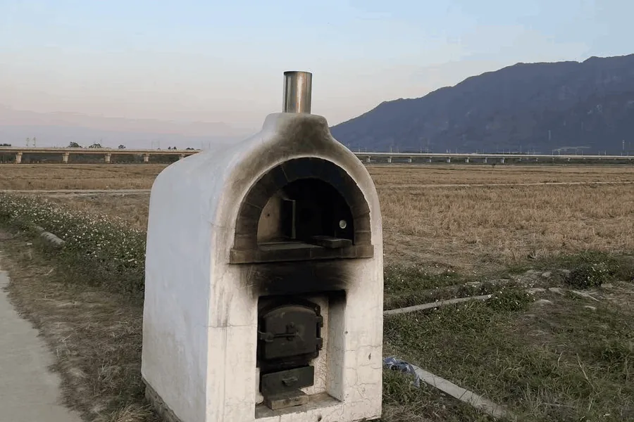 The photo: a clay oven in a field, a railway viaduct and a mountain behind it